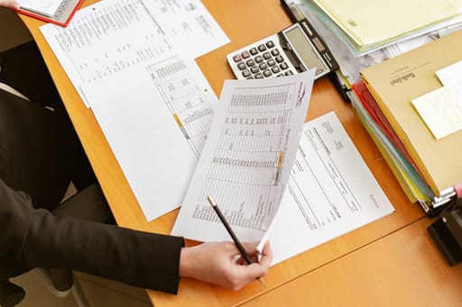 person holding paperwork, pencil and calculator at desk | Bunger Steel